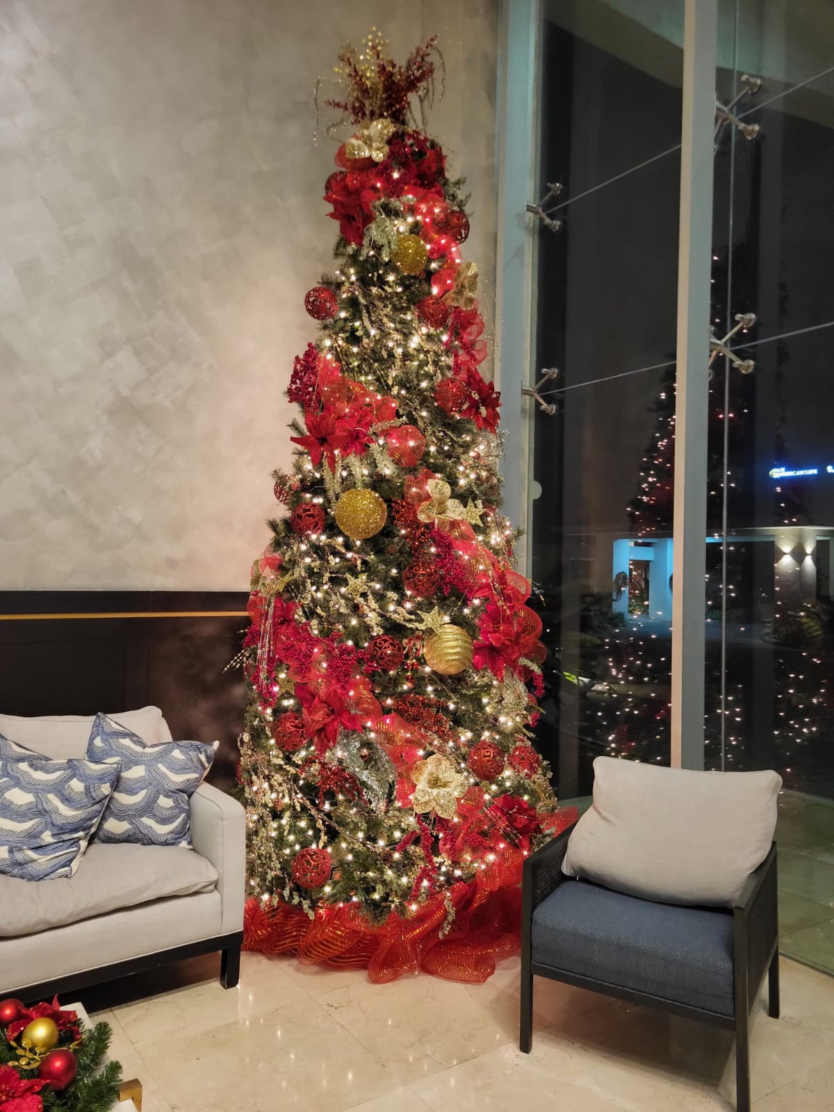 Árbol con rojo profundo y oro en sala de hotel