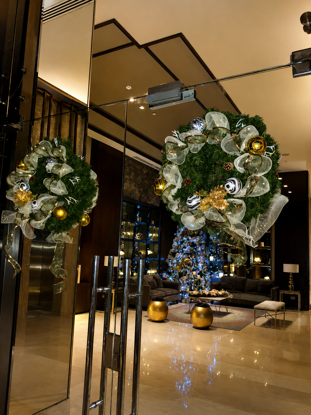 Corona navideña premium en entrada de hotel con árbol de fondo