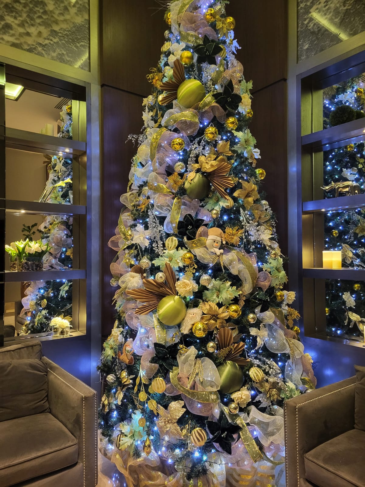 Árbol con verde oliva, negro mate y oro en lobby de lujo